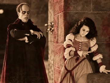 The Phantom and Christine in a scene from the 1925 silent film The Phantom of the Opera, presented in sepia with subtle burgundy accents.