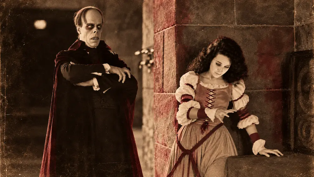 The Phantom and Christine in a scene from the 1925 silent film The Phantom of the Opera, presented in sepia with subtle burgundy accents.