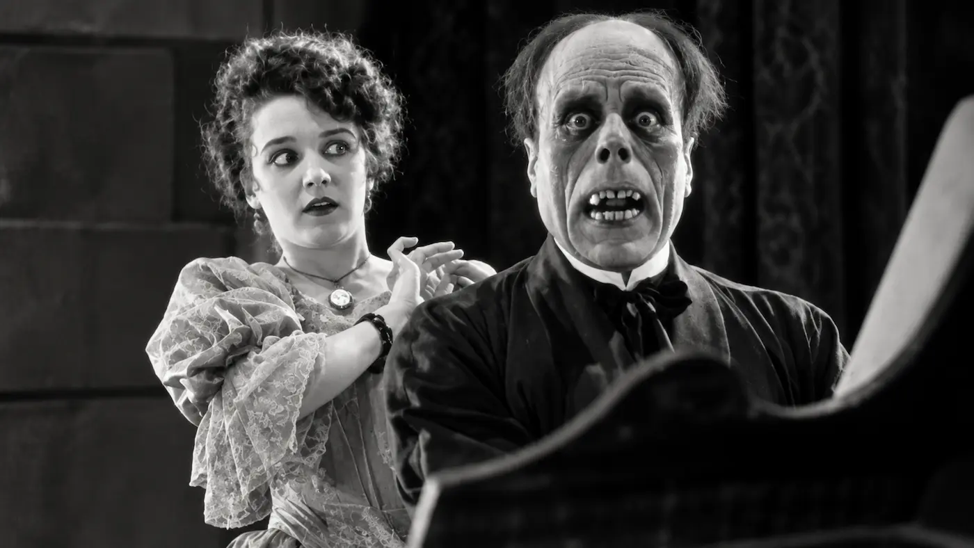 The Phantom's terrifying unmasked face with Christine standing behind him in a digitally enhanced black-and-white image inspired by The Phantom of the Opera (1925).